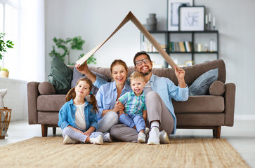 concept of housing and relocation. happy family mother father and kids with roof at home .