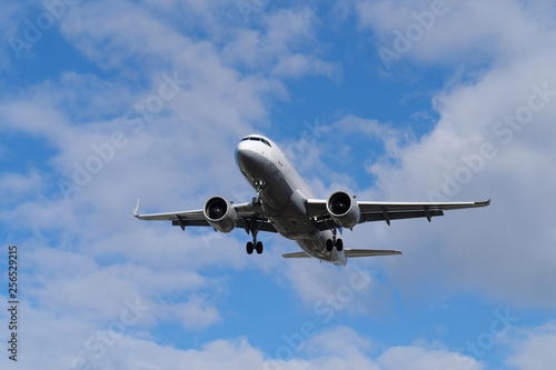 Passagierflugzeug in der Luft im Landeanflug und blauer Himmel mit weißen Wolken - Stockfoto