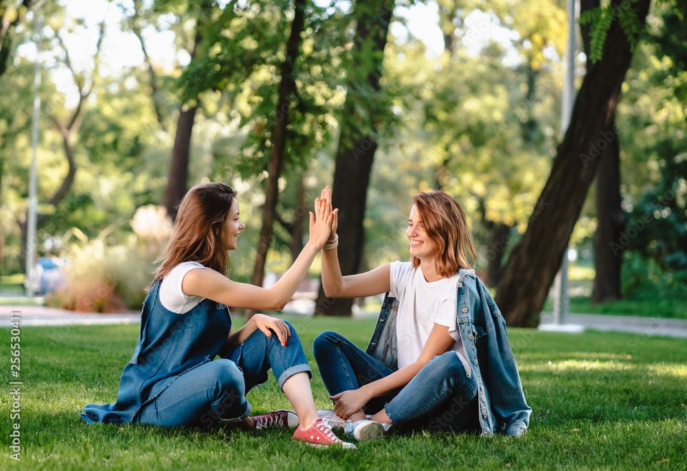 Happy female friends raising hands up giving high five in city park Happy female friends raising hands up giving high five in city park