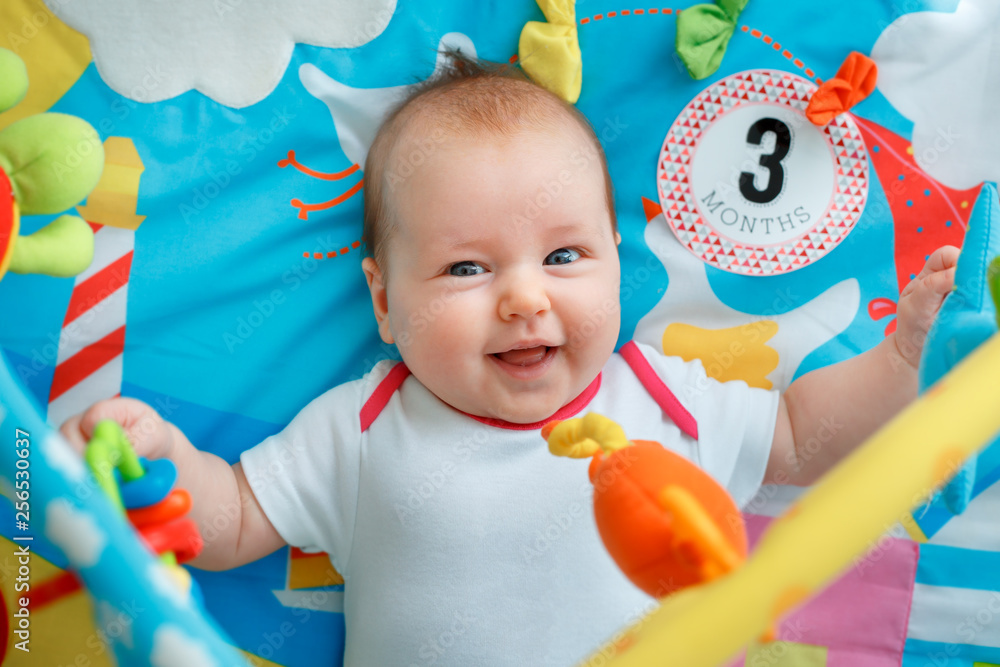 Adorable baby girl having fun with toys on colorful play mat Adorable baby girl having fun with toys on colorful play mat