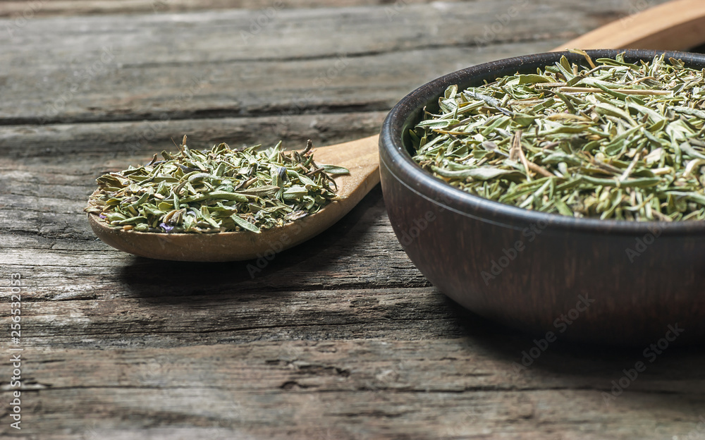 Heap of dry thyme in wooden spoon and in bowl on wooden background. Dried spice zahter thyme and oil concept Heap of dry thyme in wooden spoon and in bowl on wooden background. Dried spice zahter thyme and oil concept
