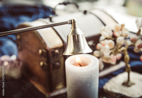 Obraz na plátně Stainless steel put out candle flame wick long handle candle snuffer bell with lit candle on esoteric background