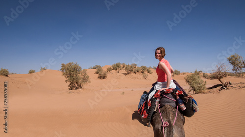 Young woman riding on dromerdary in the sahara desert-Morocco