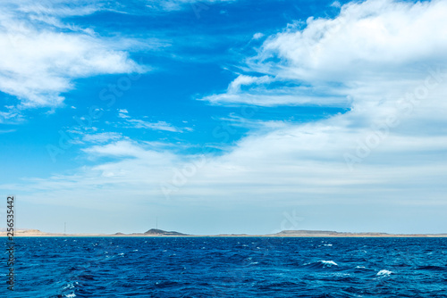 minimalistic seascape, blue sea and sky with white clouds on the whole frame