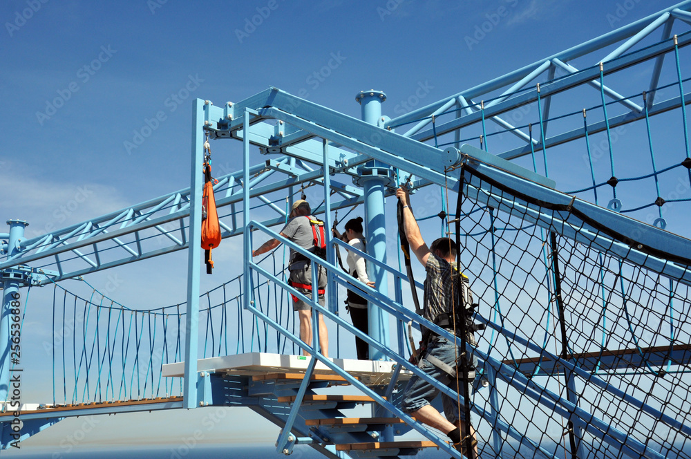 a man passes obstacles in a rope Park on the deck of the cruise ship  against the sky and the sea