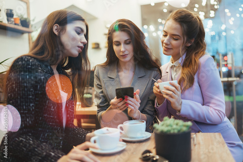 Three young attractive female entrepreneurs having meeting in cafe