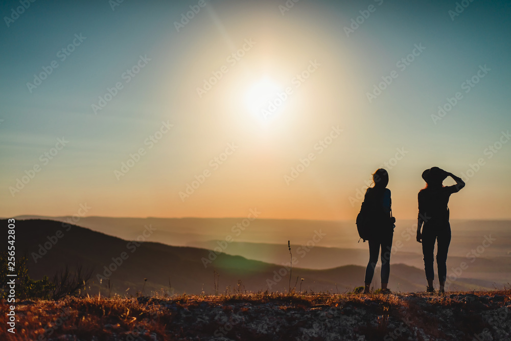 Two female hikers with backpacks at the mountain top