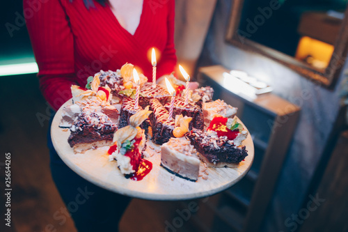 Waiter brings Birthday cake with candles in motion , bright lights at restaurant, close up view.Celebrating birthday day. Toned image. Selective focus. Design Organic Gourmet and luxury concept servi