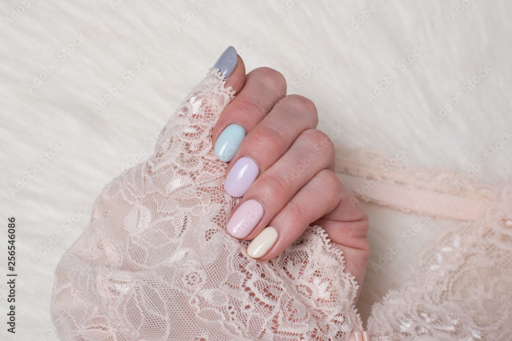 Female hand with a multi-colored gentle manicure. Lace in hand. Close-up Female hand with a multi-colored gentle manicure. Lace in hand. Close-up