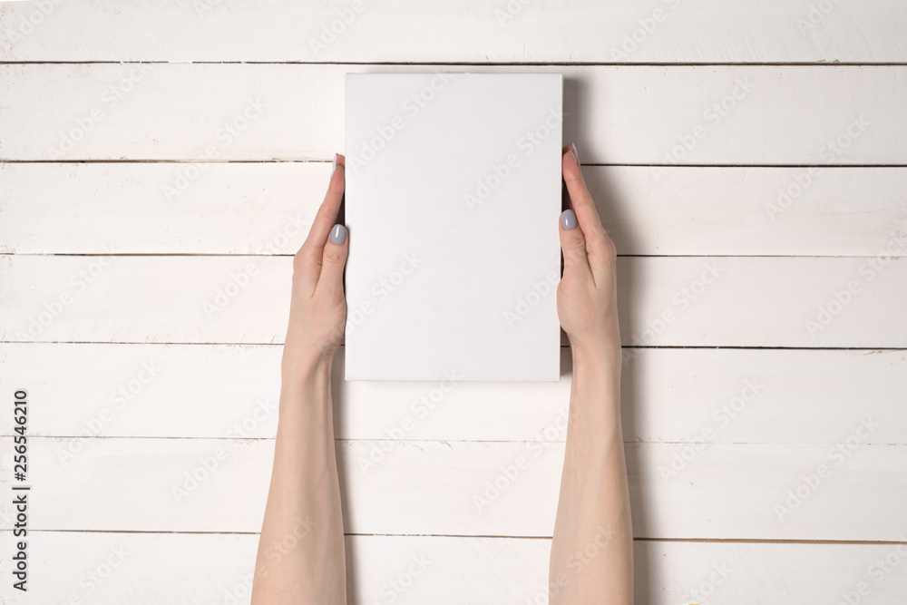 White rectangular box in female hands. Top view. White table on the background White rectangular box in female hands. Top view. White table on the background