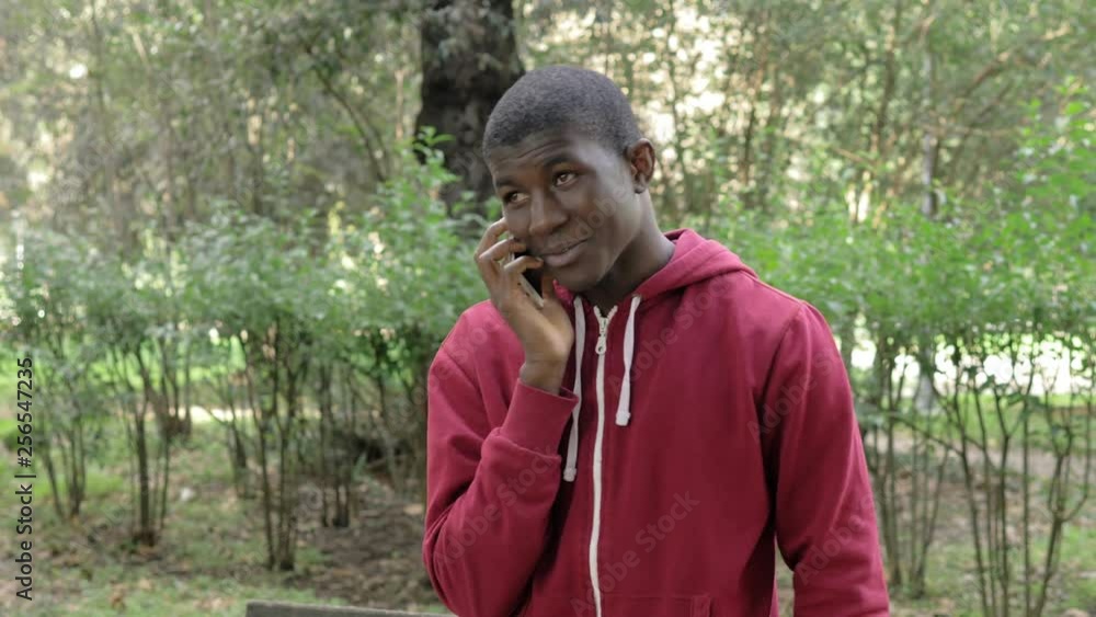Smiling relaxed american african young man talking by phone in the park Smiling relaxed american african young man talking by phone in the park