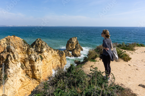 Girl looks out over cliffs in Lagos, Portugal Ponta da Piedade