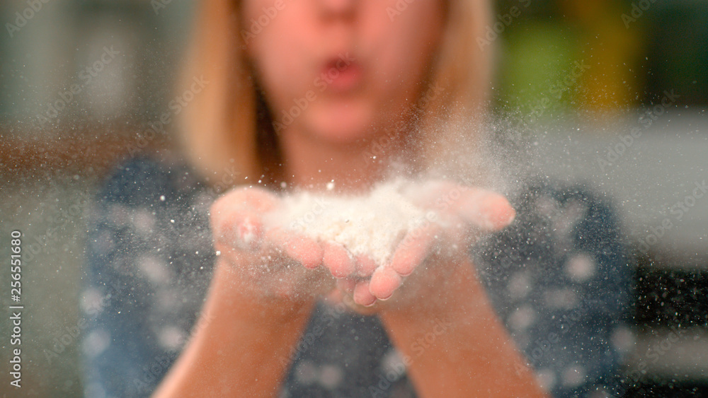 CLOSE UP, DOF: Unrecognizable woman blowing flour out of her hands and at camera