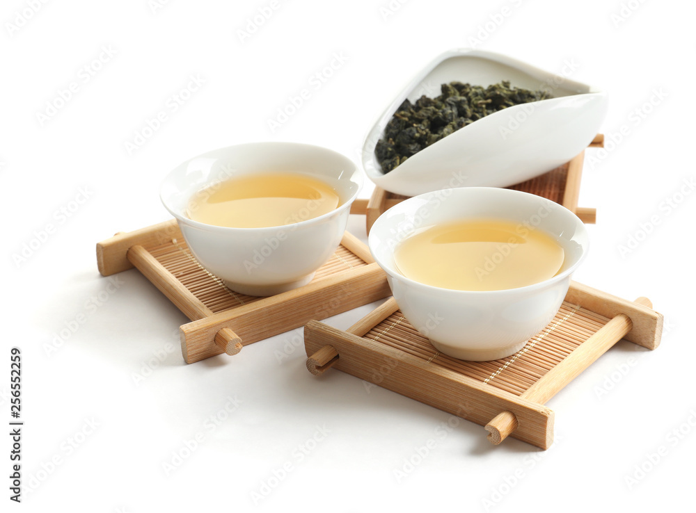 Cups of Tie Guan Yin oolong and chahe with tea leaves on white background Cups of Tie Guan Yin oolong and chahe with tea leaves on white background