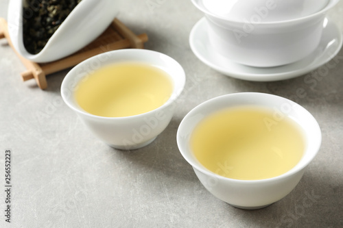Cups of Tie Guan Yin oolong tea on grey table