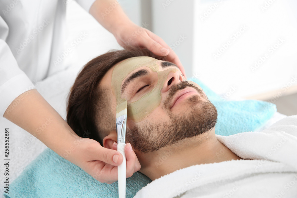 Cosmetologist applying mask on client's face in spa salon Cosmetologist applying mask on client's face in spa salon
