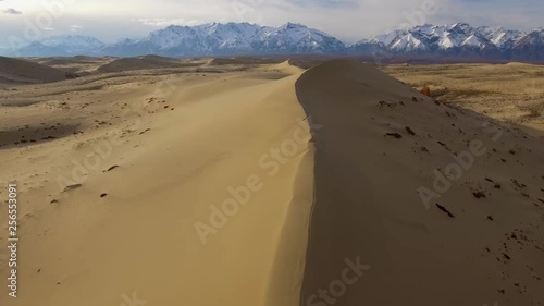 Chara Sands Desert Russia Siberia tundra Yellow gold vertex sand barkhan Natural monument Udokan snow covered mountains ranges Unique unusual place. Winter blue sky clouds. Aerial Drone low span over photo