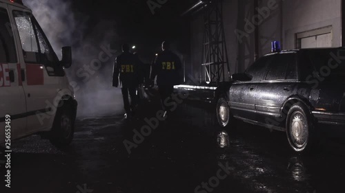 FBI agents at the crime scene, rear view. Scene. Agents of the Federal Bureau of Investigation walking in slow motion