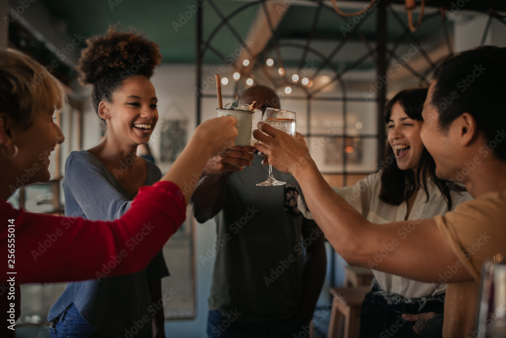 Friends cheering with drinks together in a bar at night