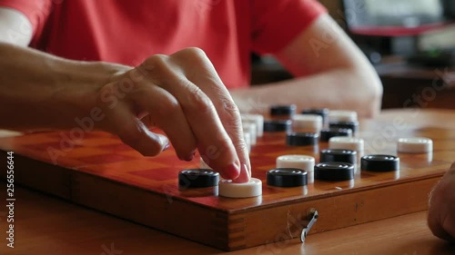 Aged couple playing checkers in Go game on the chessboard at home, close up
