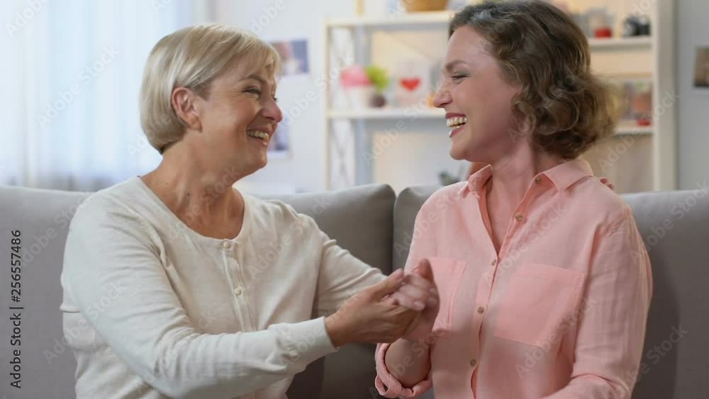 Mom and daughter laughing on couch, sharing good news, trusting conversation Mom and daughter laughing on couch, sharing good news, trusting conversation