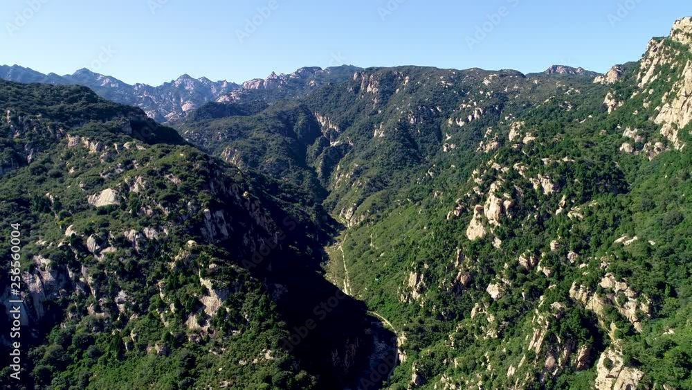 Aerial view of green mountain with dried river. Mountain peak with beautiful blue sky and green forest. Landscape of mountain in natural reserve park. Miyun, Beijing, China.