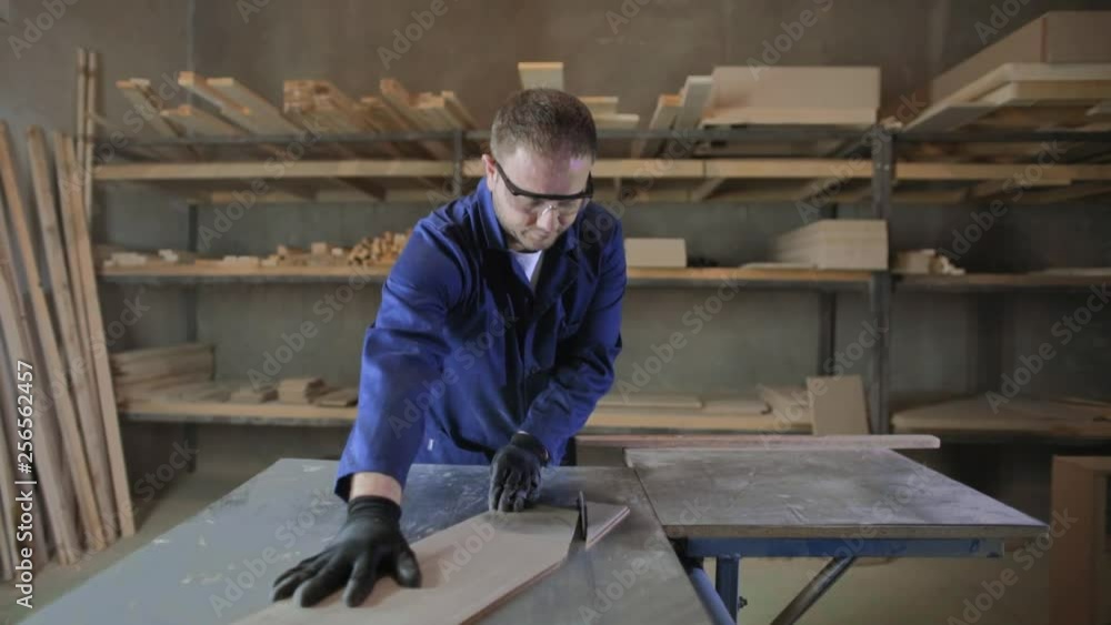 Young man in a furniture factory cutting the wooden pieces for the sofa Young man in a furniture factory cutting the wooden pieces for the sofa