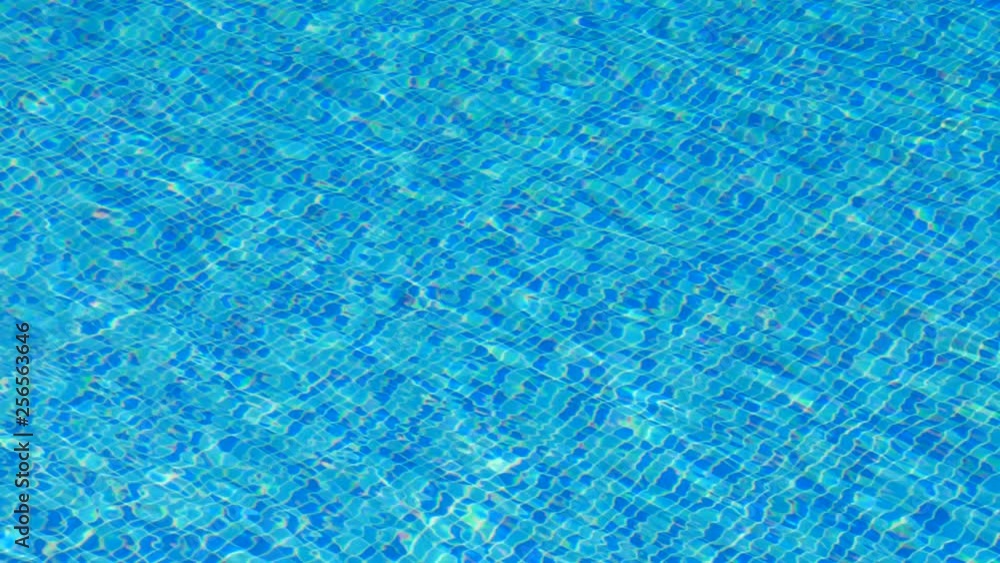 Close up shot of a pool on a sunny day with the sun refracting through the rippling water.