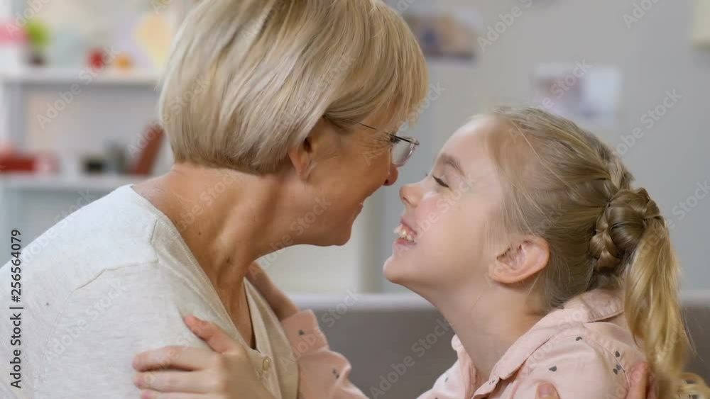 Granny and granddaughter nuzzling, playing games, having fun together, closeup Granny and granddaughter nuzzling, playing games, having fun together, closeup