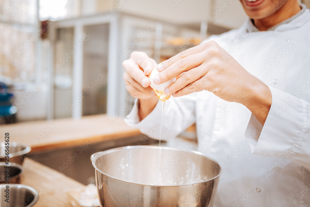 Baker wearing white jacket beating egg while cooking pastry Baker wearing white jacket beating egg while cooking pastry