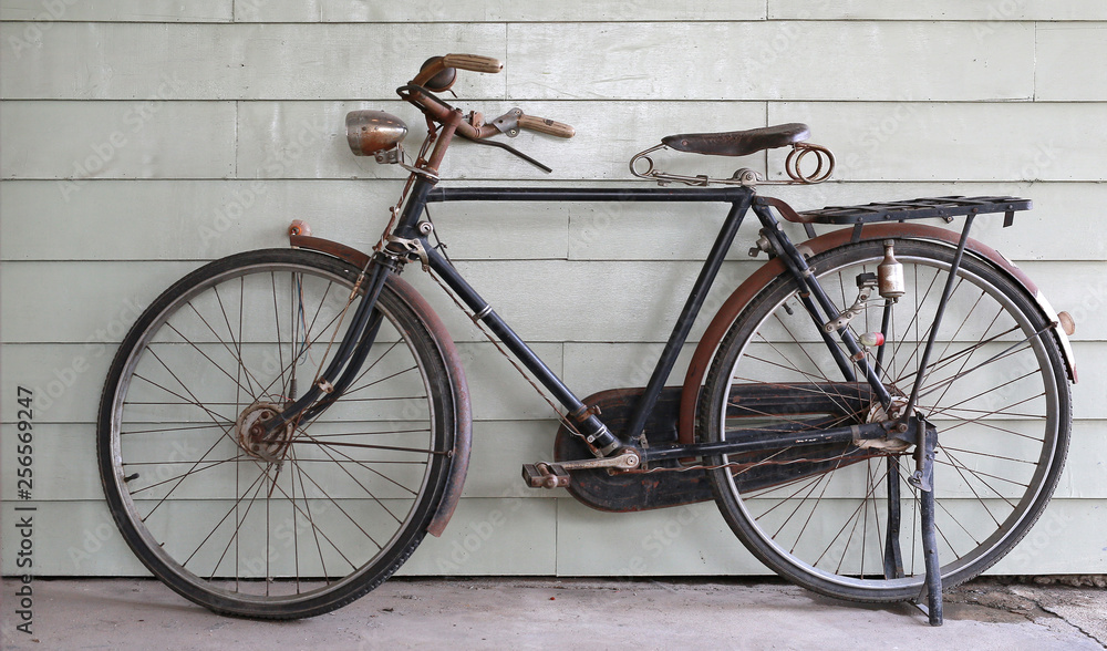 Old Ancient bicycle on the background of a gray wooden wall.