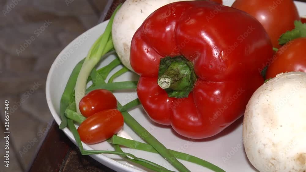 On a white plate are mushrooms, tomatoes, red peppers, green onions and parsley. On a white plate are mushrooms, tomatoes, red peppers, green onions and parsley.