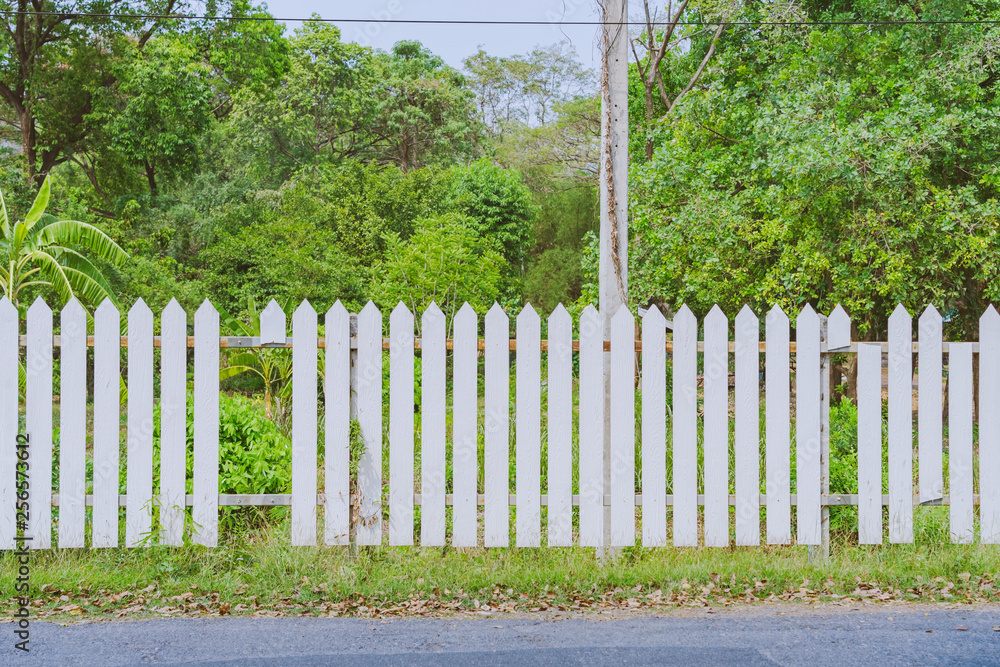 Old white wooden fence with a broken board at the roadside area