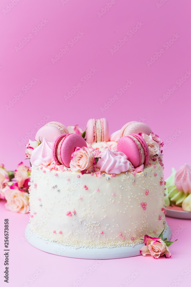 Wedding white cake with macarons and roses on a pink background Wedding white cake with macarons and roses on a pink background