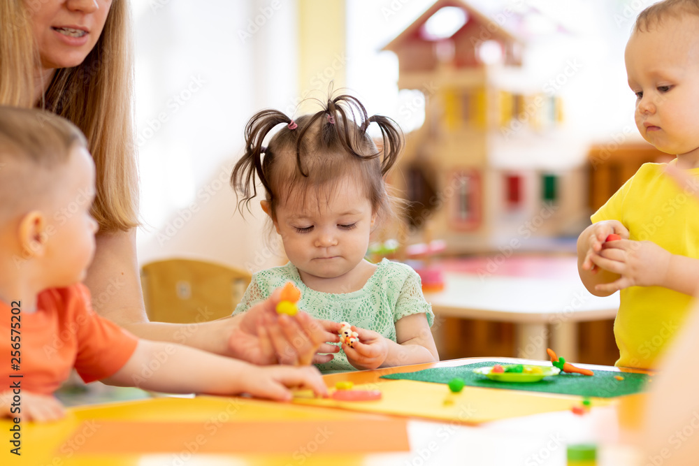 Nursery babies molded from clay toys. Teacher plays with children in kindergarten Nursery babies molded from clay toys. Teacher plays with children in kindergarten