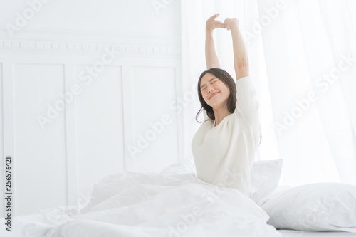 Young Asian woman in the morning she stretching in her bed in the bedroom