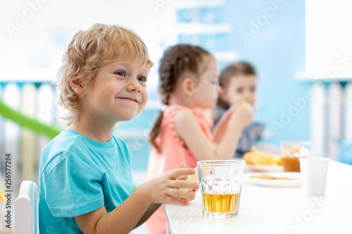 Children boy and girls smiling and eating at daycare lunch table
