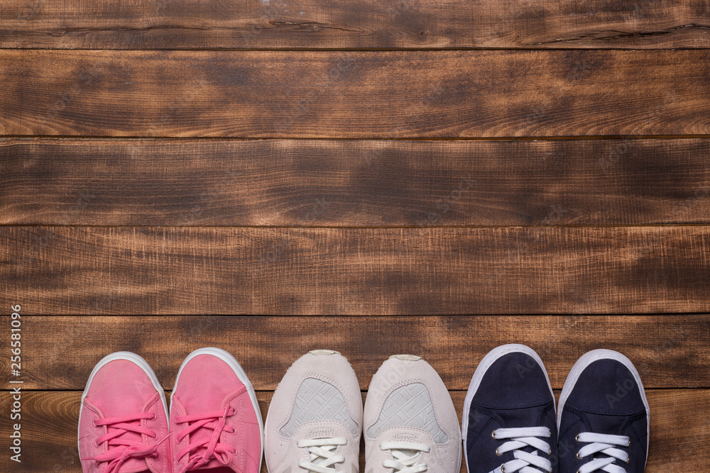 colorful  shoes top view. Set of different sneakers on wooden floor, copy space.