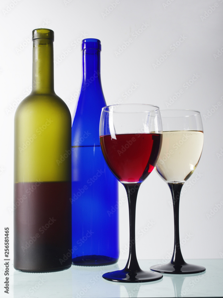 Two glasses of white and red wine and two bottles