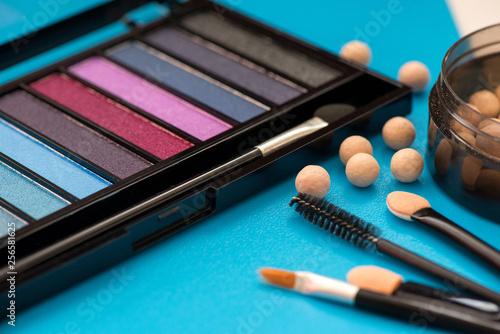 Fototapeta Naklejka Na Ścianę i Meble -  Top, up view of professional cosmetics, makeup background. Brushes, eye shadows, eyebrow pencils, powder, bronzing balls, mascara, red lipstick. Tools isolated on blue. Concept of get ready for party