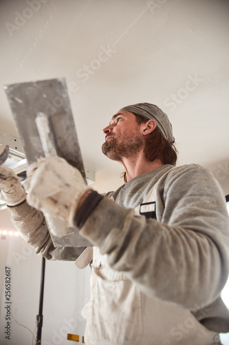 Worksman plastering gypsum walls inside the house. © astrosystem