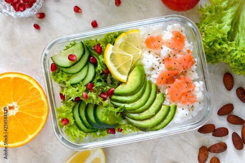 Lunch box: rice, salmon, salad with cucumber, avocado, greens. Fitness food. The concept of healthy eating. School lunch box