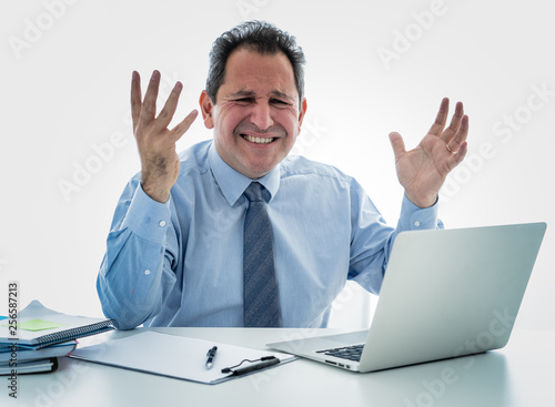 Overwhelmed and desperate mature businessman working with laptop feeling angry and furious at office