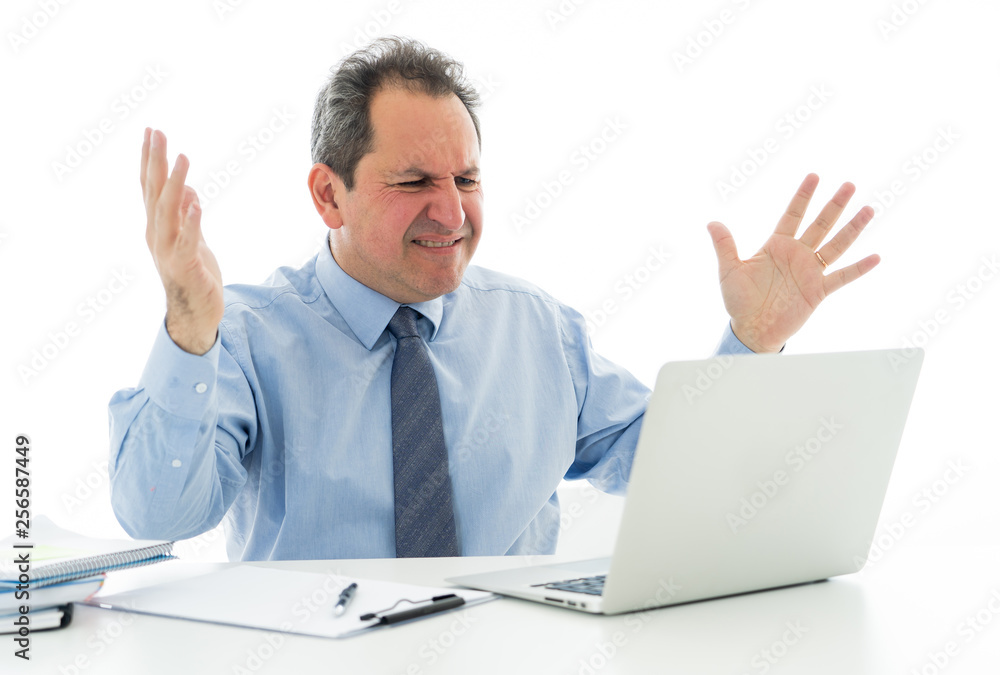 Overwhelmed and desperate mature businessman working with laptop feeling angry and furious at office Overwhelmed and desperate mature businessman working with laptop feeling angry and furious at office