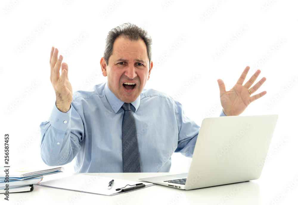 Overwhelmed and desperate mature businessman working with laptop feeling angry and furious at office Overwhelmed and desperate mature businessman working with laptop feeling angry and furious at office