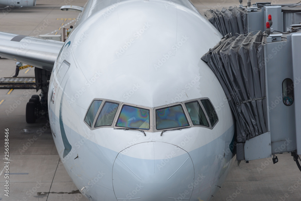 Airplane parked at airport terminal serviced by the ground crew preparing for a flight