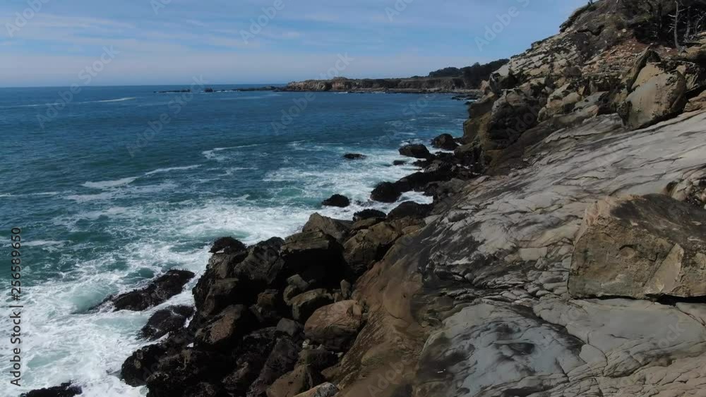 Sun drenched rocks are rhythmically beaten by Pacific Ocean Waves. Cliffs and rugged trees frame the seashore. Drone based aerial videography. Cinematic and beautiful. calming and Relaxed Euphoric Sun drenched rocks are rhythmically beaten by Pacific Ocean Waves. Cliffs and rugged trees frame the seashore. Drone based aerial videography. Cinematic and beautiful. calming and Relaxed Euphoric