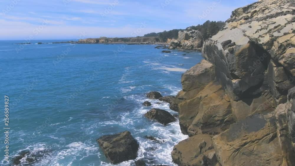 Sun drenched rocks are rhythmically beaten by Pacific Ocean Waves. Cliffs and rugged trees frame the seashore. Drone based aerial videography. Cinematic and beautiful. calming and Relaxed Euphoric Sun drenched rocks are rhythmically beaten by Pacific Ocean Waves. Cliffs and rugged trees frame the seashore. Drone based aerial videography. Cinematic and beautiful. calming and Relaxed Euphoric