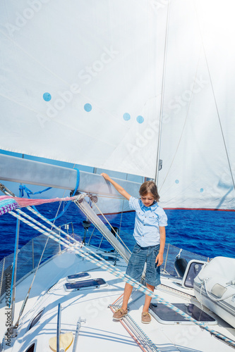 Little boy on board of sailing yacht on summer cruise. Travel adventure, yachting with child on family vacation. © Max Topchii