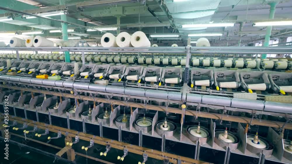Rows of spools, spinning on textile factory machines. Rows of spools, spinning on textile factory machines.